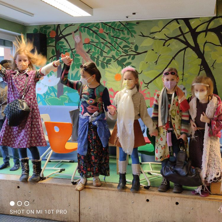 Kinder sitzen mit Gitarren in einem bunt bemalten Raum und musizieren gemeinsam.
